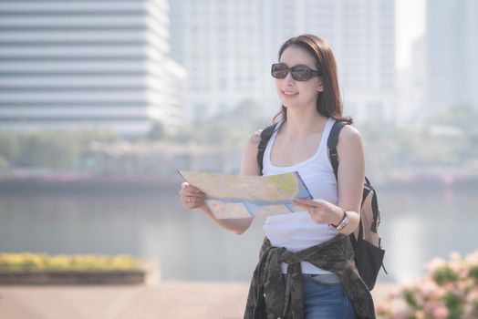 Beautiful asian solo tourist woman looking at the map searching for tourists sightseeing spot. Vacation travel in summer.