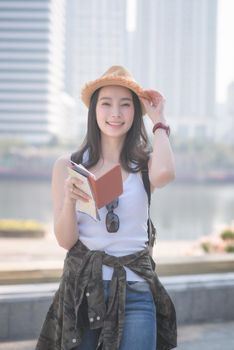 Beautiful asian solo tourist woman smiling and searching for tourists sightseeing spot. Vacation travel in summer