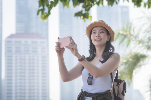 Beautiful asian solo tourist woman enjoy taking photo by smart phone at tourist sightseeing spot. Vacation travel in summer