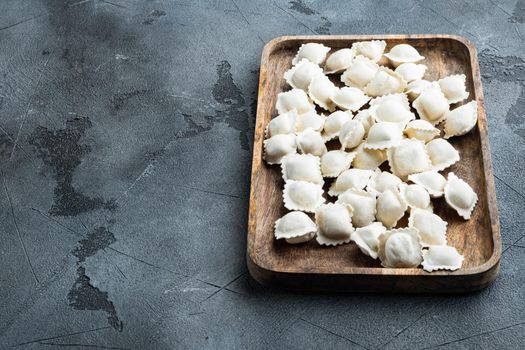 Frozen dumplings tortellini and ravioli set in wooden box, on gray background , with copyspace and space for text