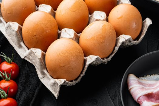 Chicken eggs in an egg box tray set, on black background