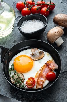 Scrambled eggs in frying pan with pork lard, bread and green feather in cast iron frying pan, on gray background