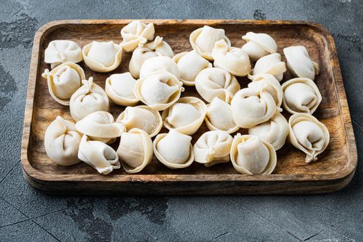 Frozen dumplings tortellini and ravioli set in wooden box, on gray background