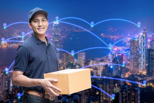 Asian delivery man holding a cardboard box with networking of internet of things in smart city for e-commerce and logistics concept.