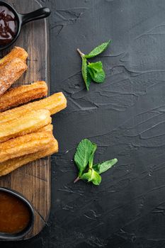 Churros with caramel, Traditional Spanish cusine, on black background, top view flat lay with space for text, copyspace