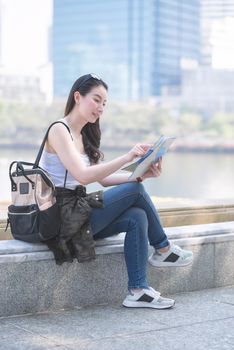 Beautiful asian solo tourist woman  looking at the map searching for tourists sightseeing spot. Vacation travel in summer.