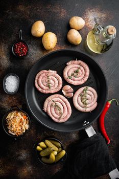 Bavarian fried sausage on sauerkraut in cast iron frying pan, on old dark rustic background, top view flat lay