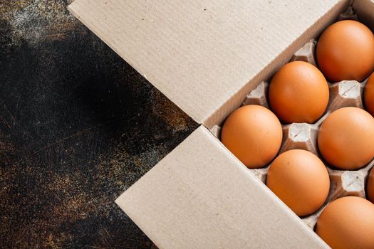 Raw chicken eggs in egg box set, on old dark rustic background, top view flat lay , with space for text copyspace