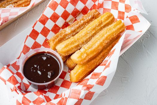 Churros with sugar powder, in the box in paper tray, on white background