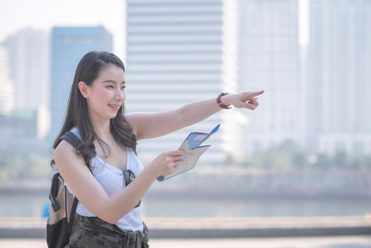 Beautiful asian tourist woman looking at the map searching for tourists sightseeing spot. Vacation travel in summer.