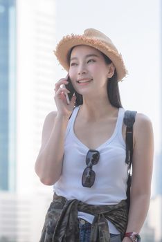 Beautiful asian solo tourist woman smiling and enjoy taking via mobile phone in city downtown. Vacation travel in summer.