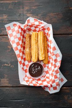 Spanish porras. Spanish food like spanish churros with chocolate, and caramel in paper tray, on old dark wooden table background, top view flat lay