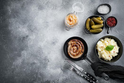 Wurst or Bratwurst with Fermented Cabbage, Pickled Cucumber, and Spices in cast iron frying pan, on gray background, top view flat lay , with space for text copyspace