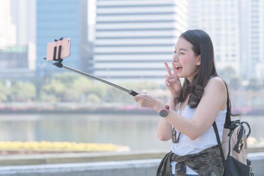 Beautiful asian tourist woman taking selfies on a smartphone in urban city downtown. Vacation travel in summer.