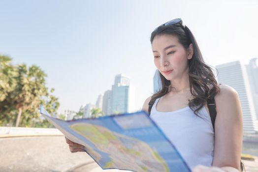 Beautiful asian tourist woman looking at the map searching for tourists sightseeing spot. Vacation travel in summer.