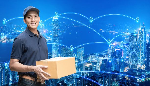 Asian delivery man holding a cardboard box with networking of internet of things in smart city for e-commerce and logistics concept.
