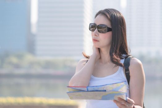 Beautiful asian tourist looking at the map searching for tourists sightseeing spot. Vacation travel in summer.