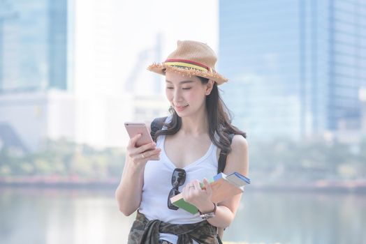 Beautiful asian tourist woman smiling and searching for tourists sightseeing spot. Vacation travel in summer.