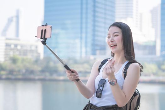 Beautiful asian woman enjoy using video call technology on a smartphone in urban city downtown. Vacation travel in summer.