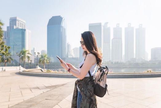 Beautiful asian tourist woman looking at mobile phone for searching location of landmark. Vacation travel in summer