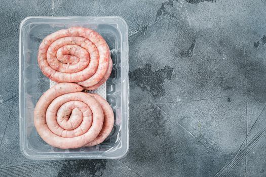 Raw meat sausage set, on gray background, in plastic pack, top view flat lay , with space for text copyspace