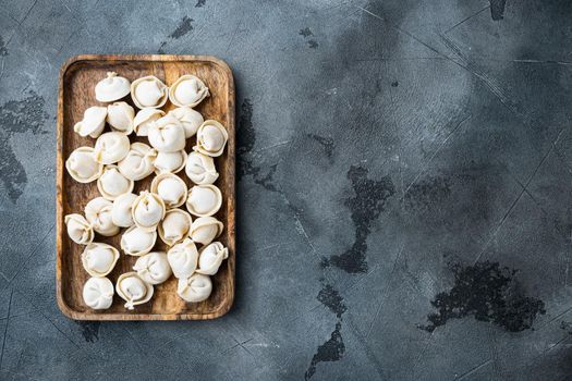 Frozen dumplings tortellini and ravioli set in wooden box, on gray background, top view flat lay , with copyspace and space for text