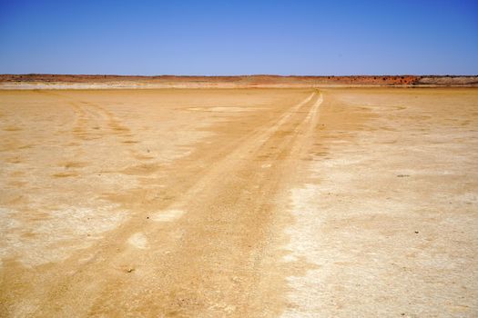 Long dirt road on a desert pan