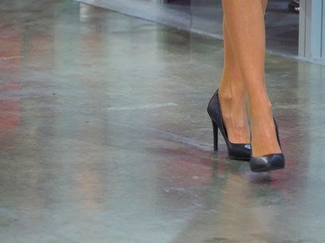 Close up of female legs steps wearing high heels elegant shoes on concrete floor