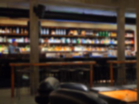 Bar counter and wide liquor bottles shelves defocused bokeh image