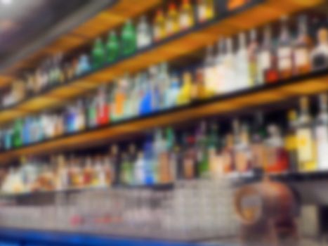 Bar counter and wide liquor bottles shelves defocused bokeh image