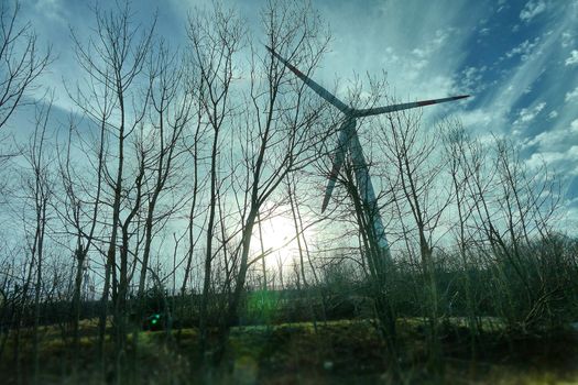 Wind turbine in natural environment near high voltage pylon