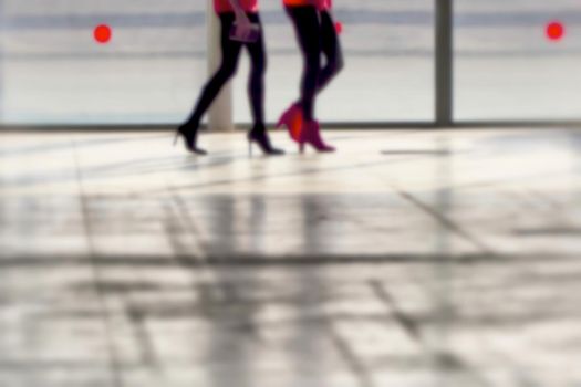 Close up legs of two women walking silhouette in blurry background