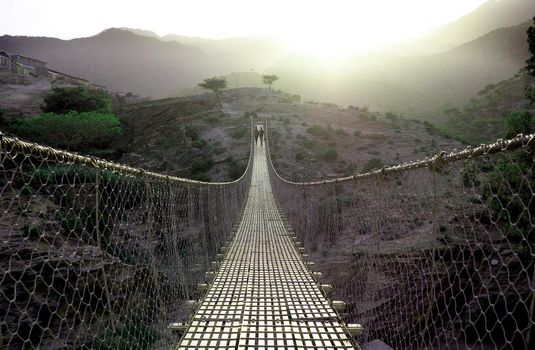 Suspension bridge over a valley at sunset