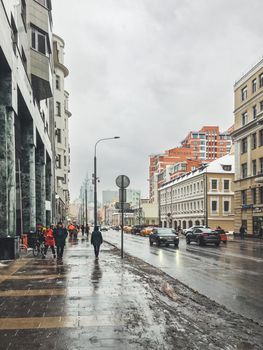 MOSCOW, RUSSIA - January 23, 2021. People and cars on wet streets of Moscow. Snow melted and mixed with mud.