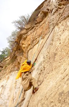 Debre damo, Ethiopia - 7 June 2019 :Monk climbing a rock wall at Debre Damo Monastery, Ethiopia