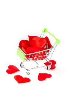 A toy cart from the supermarket filled with red hearts isolated on white background, the concept of love and Valentine's Day.