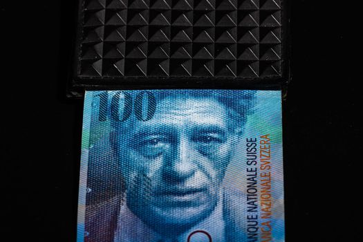 100 swiss franc banknote in a black wallet isolated.