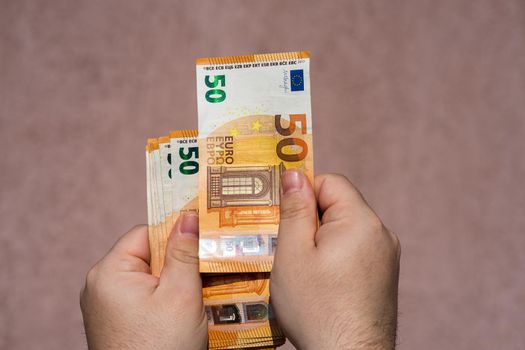 Hand holding showing euro money and giving or receiving money like tips, salary. 50 EURO banknotes EUR currency isolated. Concept of rich business people, saving or spending money.