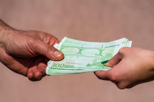 Hand giving money like bribe or tips or salary isolated, hard worked hand taking euro banknotes. Currency transfer and reward for hard work.