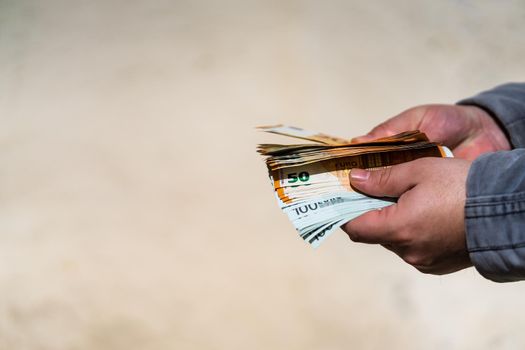 Man hand giving money like a bribe or tips. Holding EURO banknotes on a blurred background, EURO currency