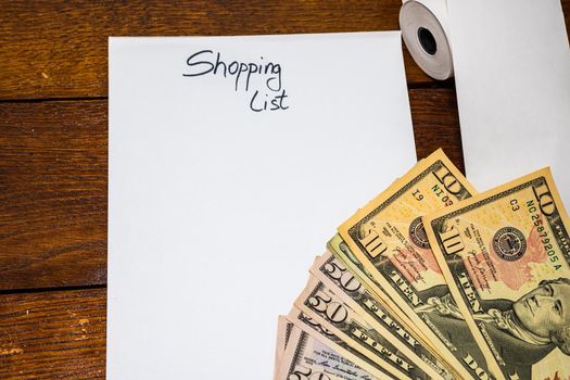 Text Shopping list on paper and empty blank tax receipt and money on table. Planning savings or business concept.