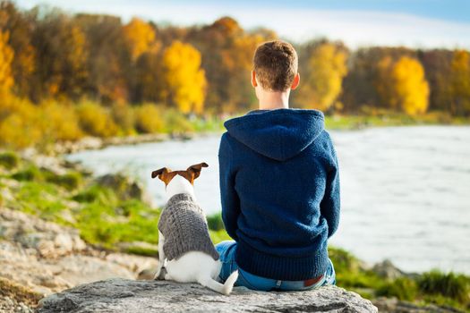 boy and his dog sitting together enjoying the view in autumn