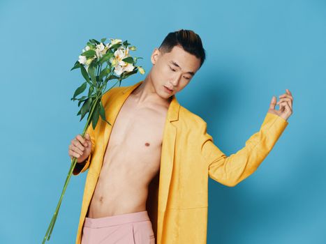korean man with bouquet of flowers in yellow coat gesturing with hands cropped view. High quality photo