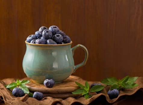 Fresh blueberry in a cup with leaves of mint.