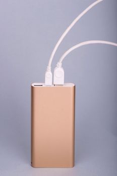 Smartphone charging with power bank on a blue background.