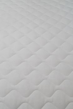 Soft white mattress close-up background with selective focus and blur.