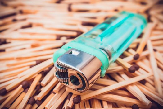 An ordinary transparent lighter lies on a pile of matches