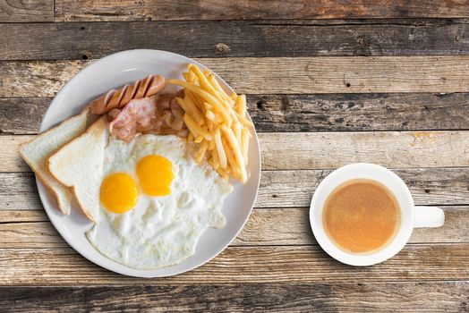 Top view of american breakfast with scrambled eggs and coffee cup on wooden table background.