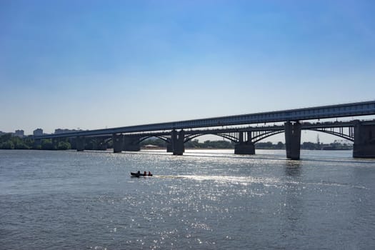 Novosibirsk, Russia. Urban landscape with a view of the bridge over the Ob river and a floating boat with people