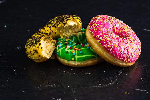 Bitten yellow glazed donut with sprinkles isolated. Close up of colorful donuts.